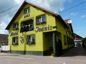 a yellow building with a sign on it at Motel Ioanis in Mîndruloc