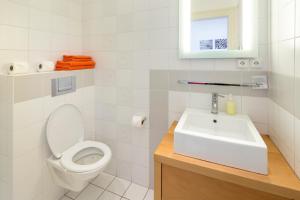 a white bathroom with a toilet and a sink at Dušní Apartments in Prague