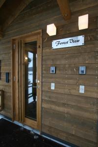 una porta d'ingresso di un edificio in legno con un cartello sopra di Forest View a Furano