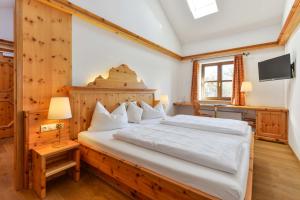 Schlafzimmer mit einem großen Bett mit einem Kopfteil aus Holz in der Unterkunft Landgasthof zum Erdinger Weissbräu in Rosenheim