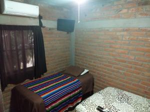 a room with a brick wall and a bed and a tv at Posada Don Jose in El Fuerte