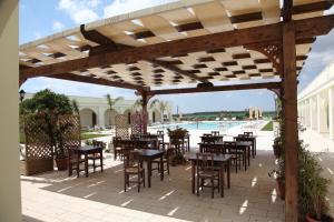 an outdoor patio with tables and chairs and a pool at Agri Hotel Conte Salentino in Porto Cesareo