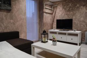 uma sala de estar com uma televisão, um sofá e uma mesa em Les logis de la maisonnette em Mouchamps