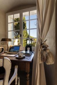 a desk with a laptop computer on it next to a window at Maison de charme Pampelonne Saint Tropez in Saint-Tropez