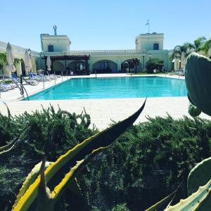 a large swimming pool with chairs and a building at Agri Hotel Conte Salentino in Porto Cesareo