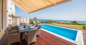 un patio con mesa y sillas junto a una piscina en Luxury Bay View Villa 20 Right On Τhe Beach en Protaras