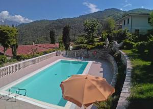 a swimming pool with an umbrella next to a house at Appartamenti La Tartufaia Country house pool and relax By Gardadomusmea in Tremosine Sul Garda