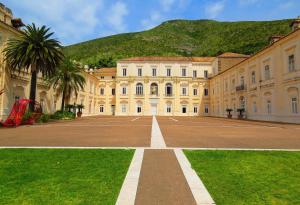 a large building with palm trees in front of it at Residenza Carlo di Borbone in Caserta