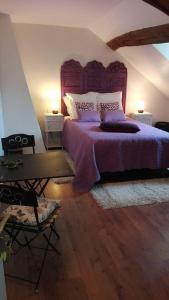 a bedroom with a purple bed and a desk at Le Pré Vert in Crugey