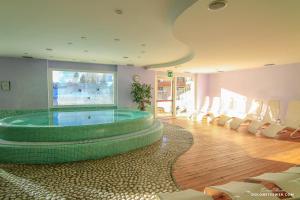 a room with a large pool with chairs in it at Hotel Savoia dal 1924 in San Martino di Castrozza