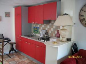 a kitchen with red cabinets and a sink at B&B Bij de Boomgaard in Tricht