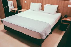 a bedroom with a large bed with white sheets and pillows at Occitano Apart Hotel in Piracicaba