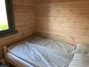 a bed in a room with a wooden wall at Morskieustronie in Ustronie Morskie