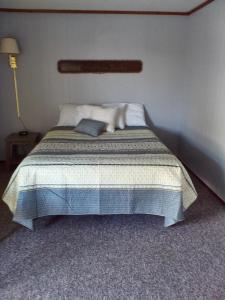 um quarto com uma cama com um cobertor azul e branco em The Monarch Motel em Cheboygan