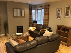 a living room with a leather couch and a fireplace at The Sidings in Enniskillen