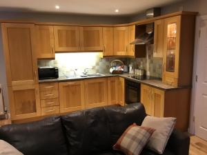 a kitchen with wooden cabinets and a black leather couch at The Sidings in Enniskillen