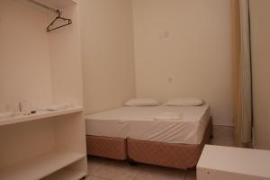 a small room with a bed and a mirror at Hotel Marina Torrano in Trindade