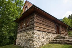a log cabin with a stone wall and windows at Chata pod Rozsutcom in Terchová