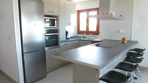 a kitchen with a stainless steel refrigerator and stools at Casa Playa in Tavernes de Valldigna