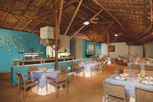 uma sala de jantar com mesas e cadeiras e uma cozinha em Dreams Huatulco Resort & Spa em Santa Cruz, Huatulco