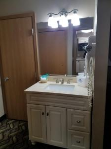 a bathroom with a sink and a large mirror at Americas Best Value Inn and Suites Bismarck in Bismarck