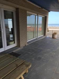 a wooden bench sitting on a patio with a view of the beach at Au gré du vent in Koksijde