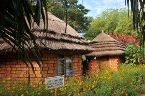 a small house with a thatched roof and a sign in front at New Court View Hotel in Masindi