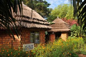 a small brick house with a thatched roof at New Court View Hotel in Masindi