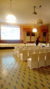 una sala conferenze con sedie bianche e uno schermo di proiezione di Hotel Castello a Montjovet