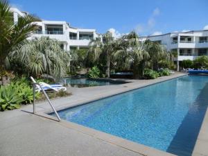 a swimming pool with a chair in front of a building at Cutterscove Resort Apartments in Mount Maunganui