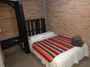 a bed with a blanket on it next to a brick wall at Posada Don Jose in El Fuerte