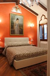 ein Schlafzimmer mit einer orangefarbenen Wand mit einem Bild einer Frau in der Unterkunft Casa Torretta in Venedig