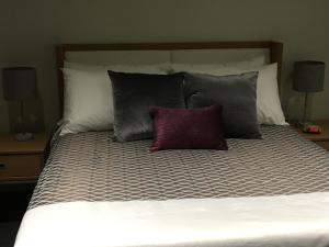 1 cama con 4 almohadas y 2 lámparas en University of Alberta - PLH Accommodation, en Edmonton
