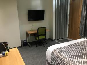 a hotel room with a bed and a desk and a television at University of Alberta - PLH Accommodation in Edmonton