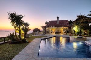 a house with a swimming pool in front of the ocean at Villa Sunrise Lagonisi in Lagonissi