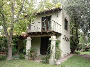 a white house with a balcony and trees at La Chacrita in Chacras de Coria