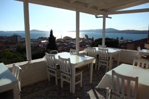 un patio con tavoli, sedie e vista sull'oceano di Cesmeli Han a Ayvalık