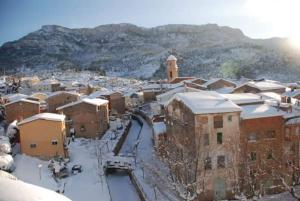une ville avec des bâtiments enneigés et une tour d'horloge dans l'établissement Ca la Monica, à Torre de Fontaubella