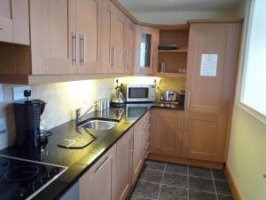 a kitchen with wooden cabinets and a sink at Castle Quay Holiday Homes in Kinsale