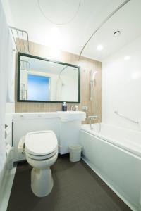 a white toilet sitting next to a white sink at HOTEL FUKURACIA OSAKA-BAY in Osaka