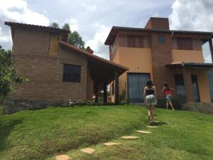 two girls walking in front of a house at Chalé Ibiti in Conceição da Ibitipoca