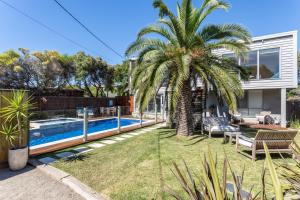 a backyard with a palm tree and a swimming pool at Front Beach House in Blairgowrie