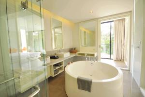 a bathroom with a large tub and a glass shower at Botanica Khao Yai by Scenical in Mu Si