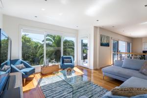 a living room with blue furniture and large windows at Front Beach House in Blairgowrie