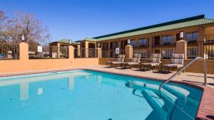 une piscine avec des chaises et des tables dans un hôtel dans l'établissement Best Western Eunice, à Eunice