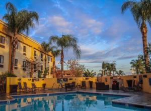 a swimming pool in front of a hotel with palm trees at Best Western Plus Arrowhead Hotel in Colton