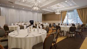 una sala de conferencias con mesas y sillas blancas y lámparas de araña en Genetti Hotel, SureStay Collection by Best Western, en Williamsport