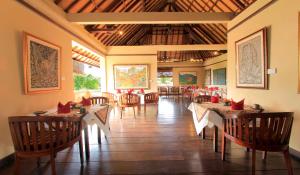 - un restaurant avec des tables et des chaises dans une salle dans l'établissement The Sungu Resort & Spa, à Ubud