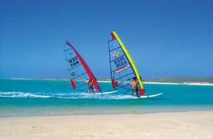 two people are wind surfing on the beach at Fully Airconditioned Geraldton Holiday Unit with free Streaming in Geraldton