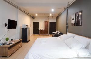 una camera con un grande letto bianco e una TV di Pann Residence a Bangkok